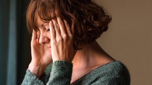 woman with a headache from the stress of caregiver burnout