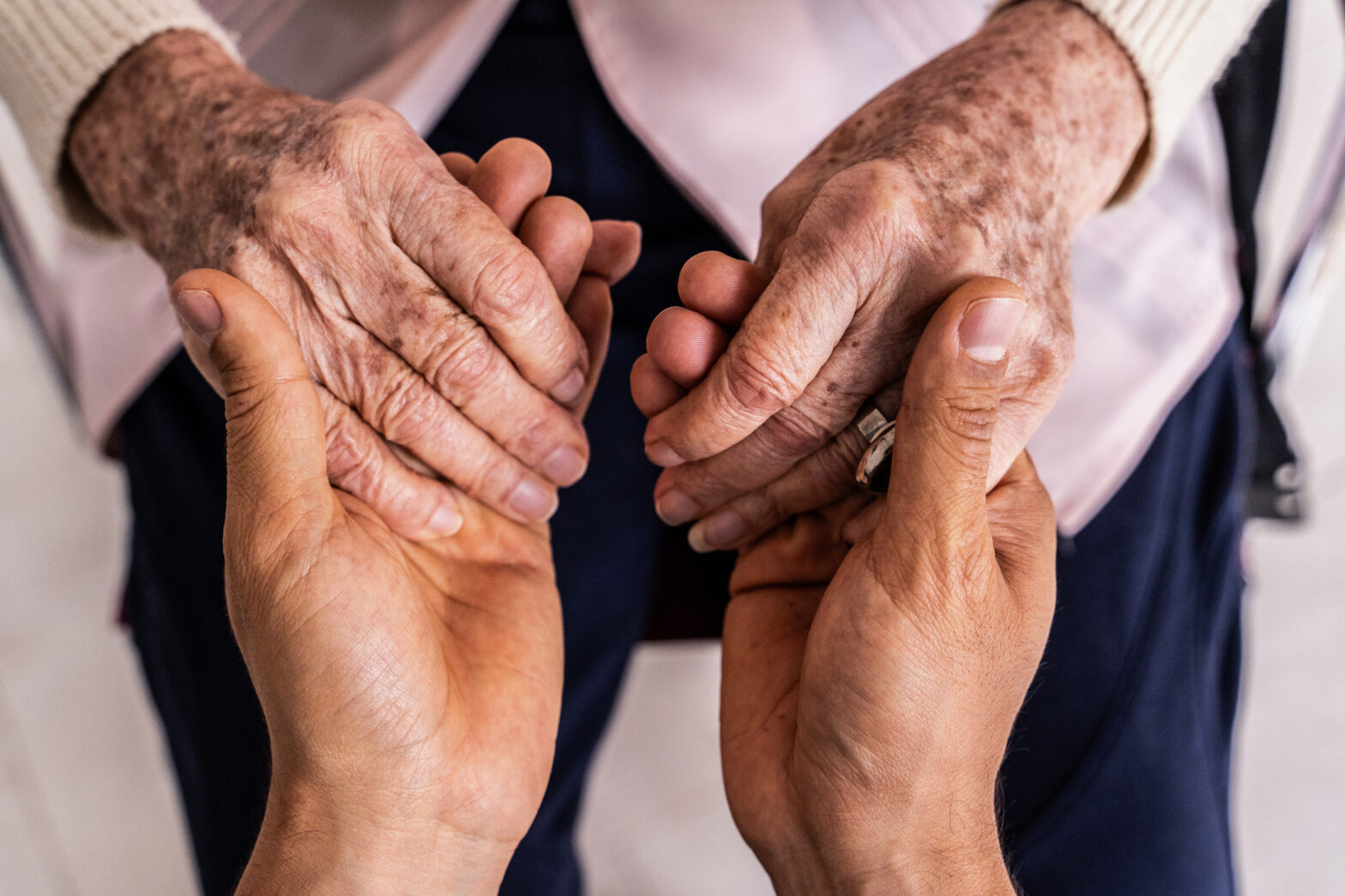 close up of caregiver's hands holding senior woman's hands