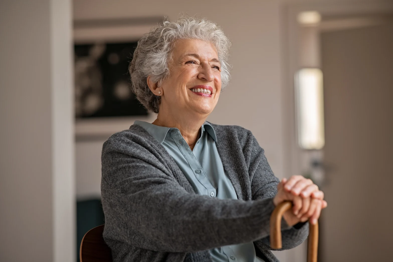 senior resting hands on cane and sitting, happy she gets private duty home care services