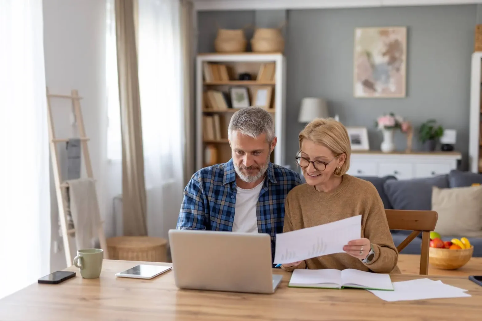 A senior couple sitting down, on their laptop and investigating the cost of assisted living in Worcester, MA, as they prepare for retirement.